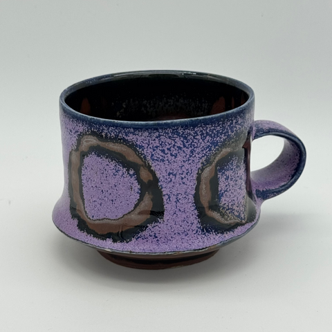 Purple ceramic mug with abstract design on a white background